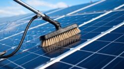 Szczotka z wodą czyszcząca powierzchnię paneli fotowoltaicznych w słoneczny dzień.